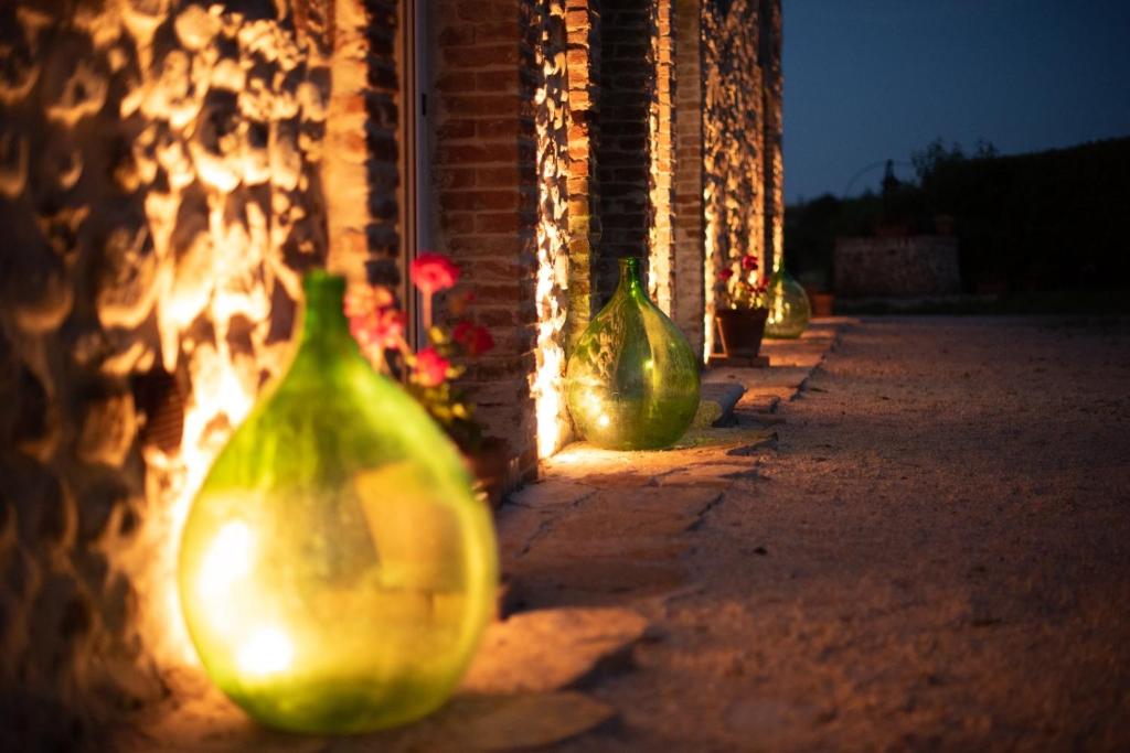 una fila di vasi di vetro verde allineati contro un edificio di Arcadia Agriturismo a San Nicola Manfredi