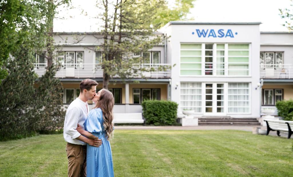 a man and a woman standing in front of a building at Wasa Historical 1938 Boutique Hotel in Pärnu