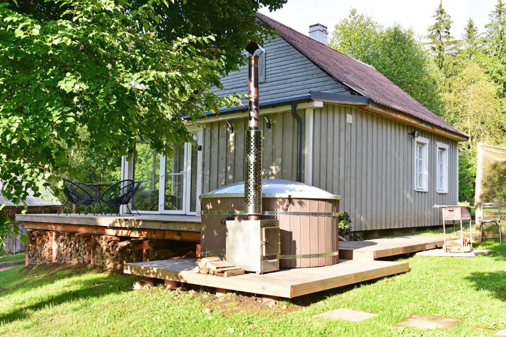 a small house with a hot tub in the yard at Namelis ant ežero kranto "Mėlynas namelis" in Tytuvėnai
