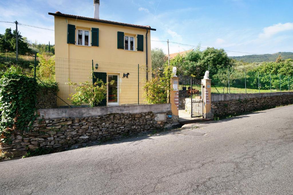 una casa amarilla con una pared de piedra y una puerta en Villa nel Borgo, en Borgomaro