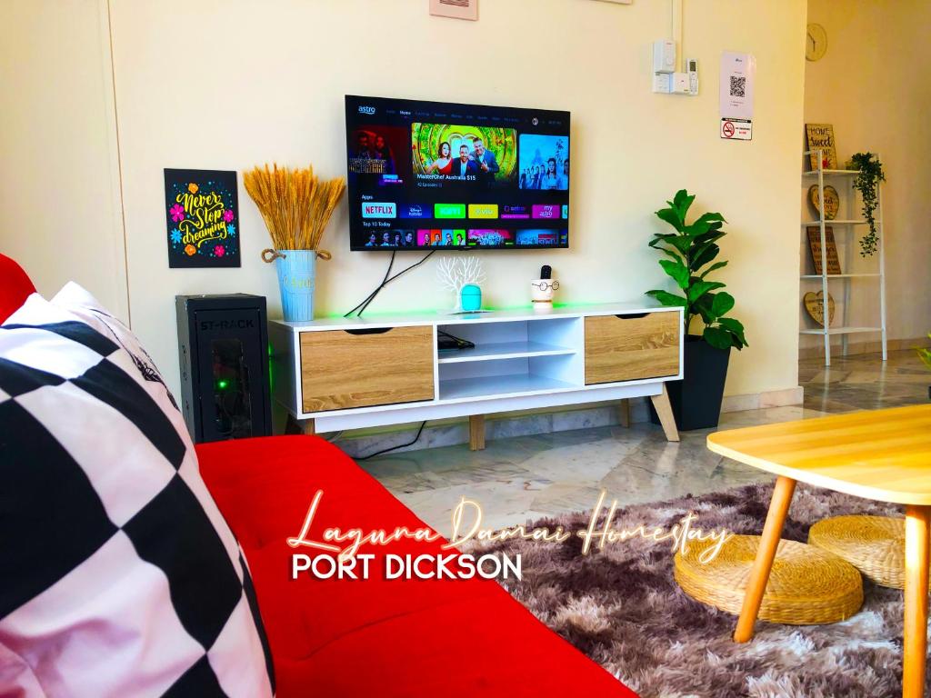 a living room with a red couch and a flat screen tv at Laguna Damai Homestay PortDickson - "PoolView & BeachNearby" in Port Dickson