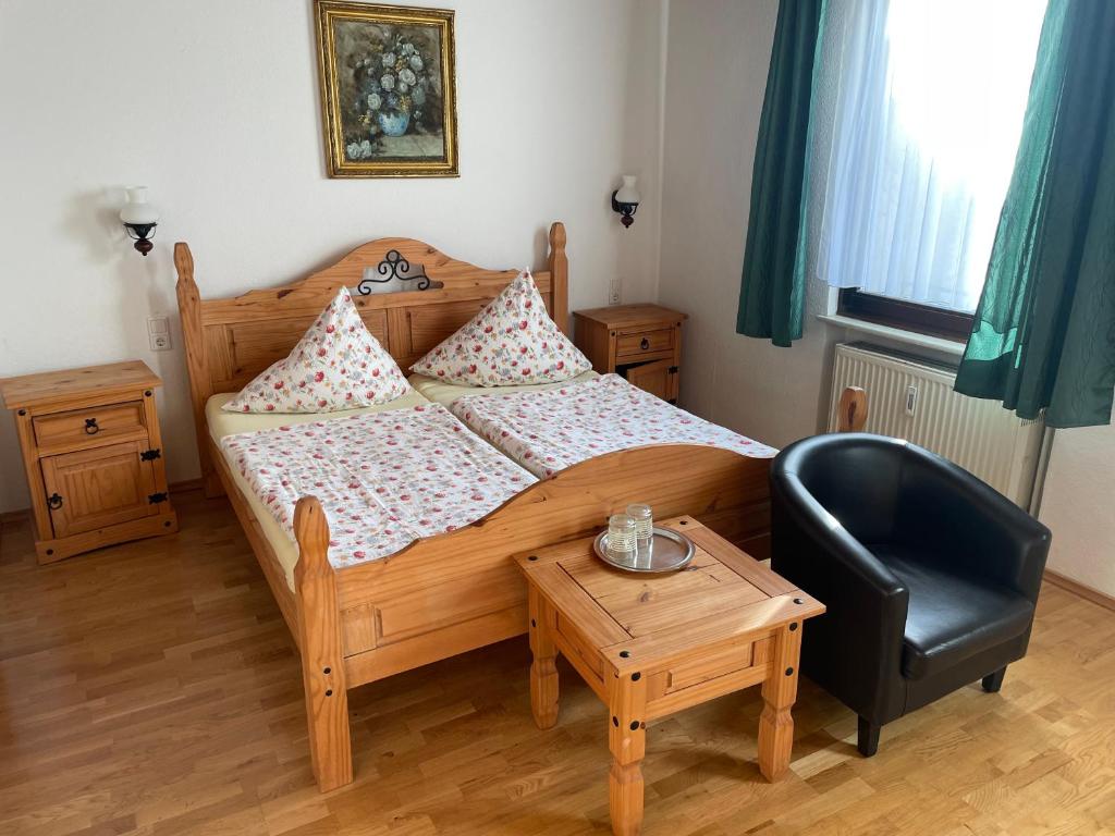 ein Schlafzimmer mit einem Bett, einem Stuhl und einem Tisch in der Unterkunft Hotel Klement in Zehdenick