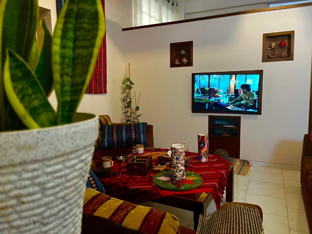 - un salon avec une table et une télévision dans l'établissement Beit Zaman hostel, à Bayt Sāḩūr