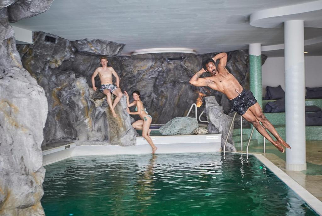 a group of people jumping into the water in a pool at Hotel Saalbacher Hof in Saalbach-Hinterglemm