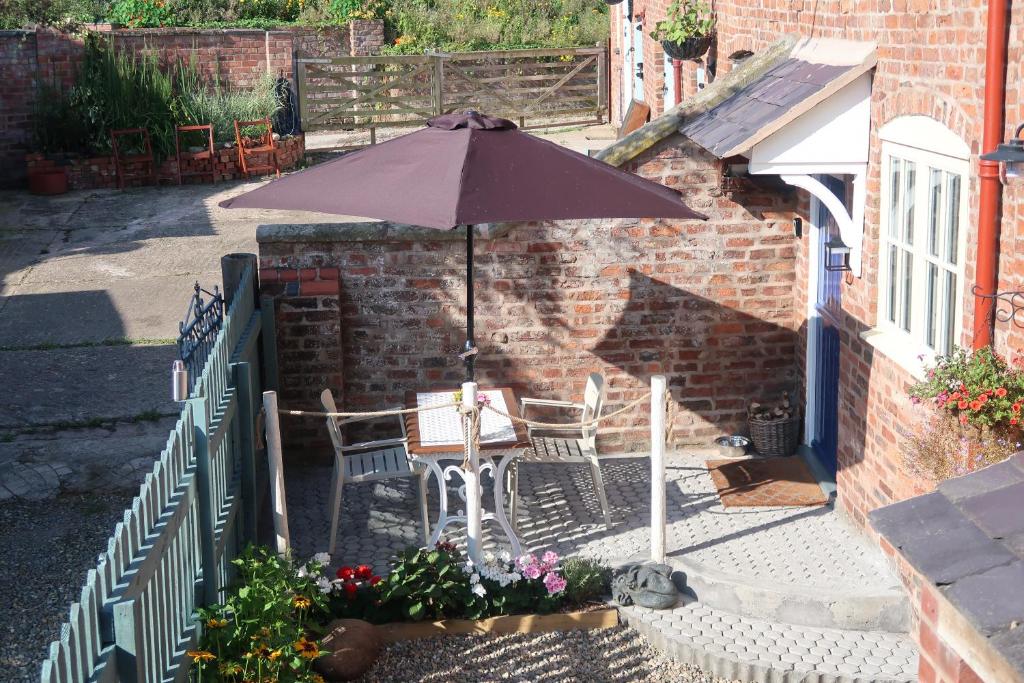 a table and chairs with an umbrella in a courtyard at The Old Pantry at Hill Farm in Penley
