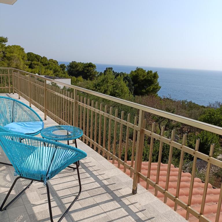 2 sillas azules sentadas en un balcón con vistas al océano en Living Castro Apartments, en Castro di Lecce