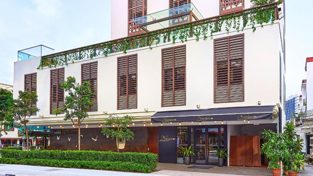 een wit gebouw met bruine luiken en planten bij Nostalgia Hotel in Singapore