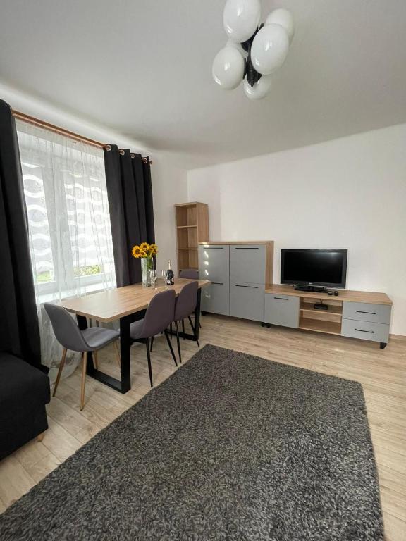 a living room with a dining room table and a television at Apartament na Piaskach in Ostrowiec Świętokrzyski