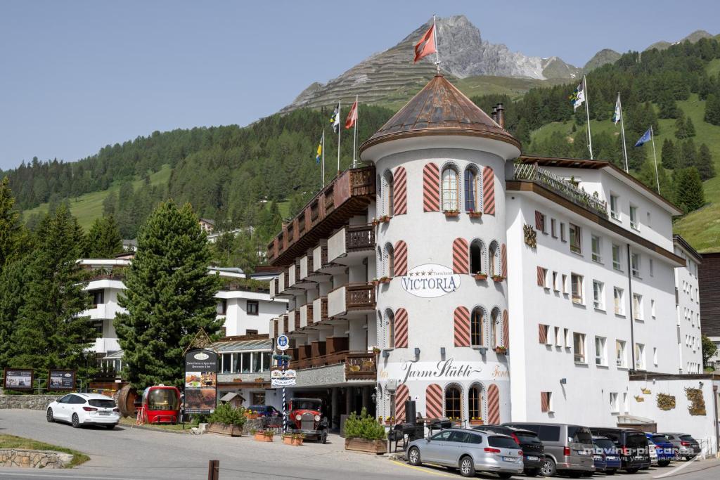 un hôtel dans les montagnes avec des voitures garées devant lui dans l'établissement Swiss Quality Turmhotel Victoria, à Davos