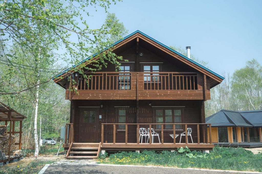 a large wooden house with two chairs on the porch at The Lodge 弟子屈 in Teshikaga