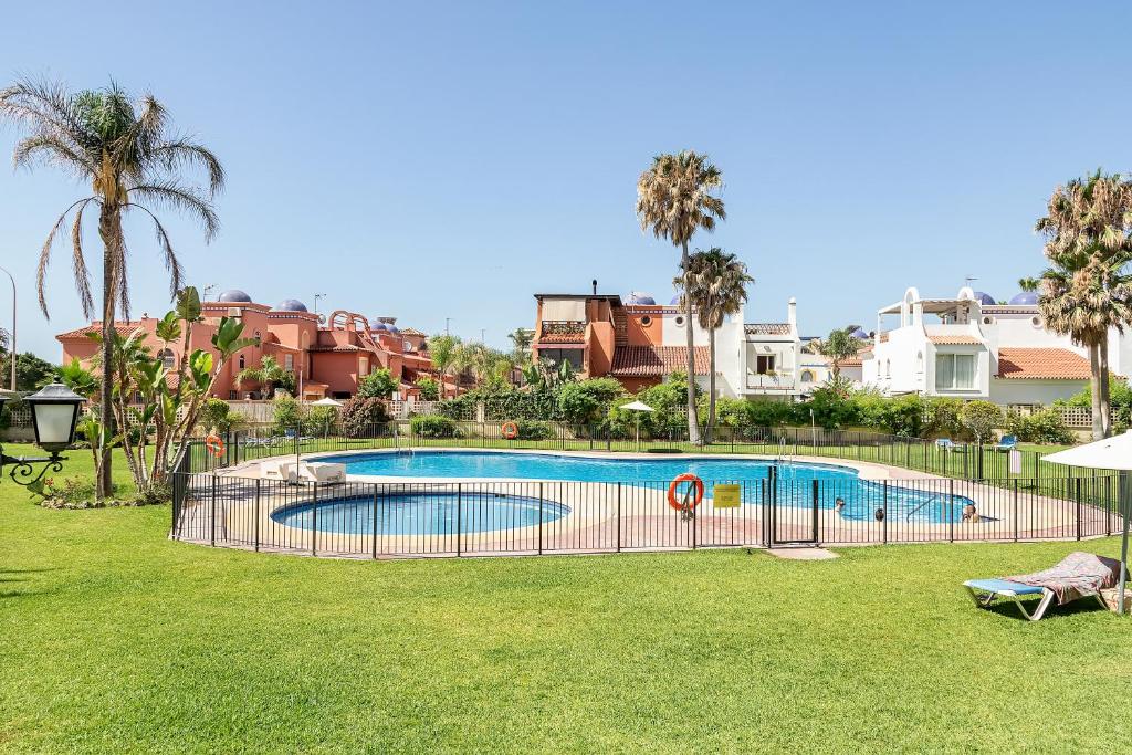 a swimming pool in a yard with palm trees and houses at Exclusive Alamos Beach in Torremolinos