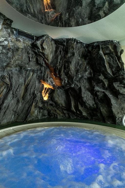 a large pool of water in a room with a rock wall at Hotel Saalbacher Hof in Saalbach-Hinterglemm