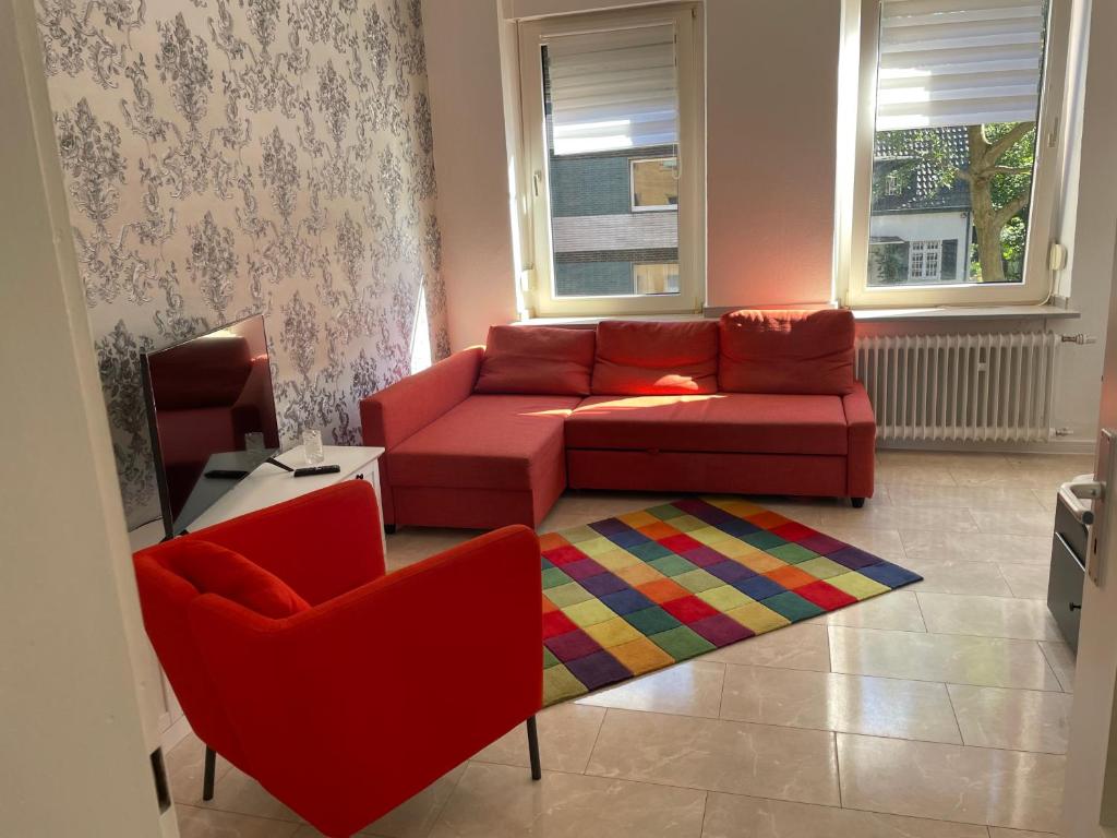 2Schlafzimmer, Wohnküche&Balkon في أوبرهاوزن: غرفة معيشة مع أريكة حمراء وكرسيين