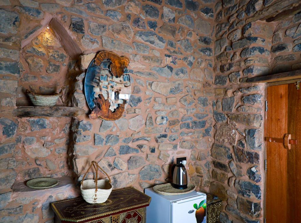 a kitchen with a stone wall with a refrigerator at Hanging Terraces المدرجات المعلقة in Al ‘Aqar