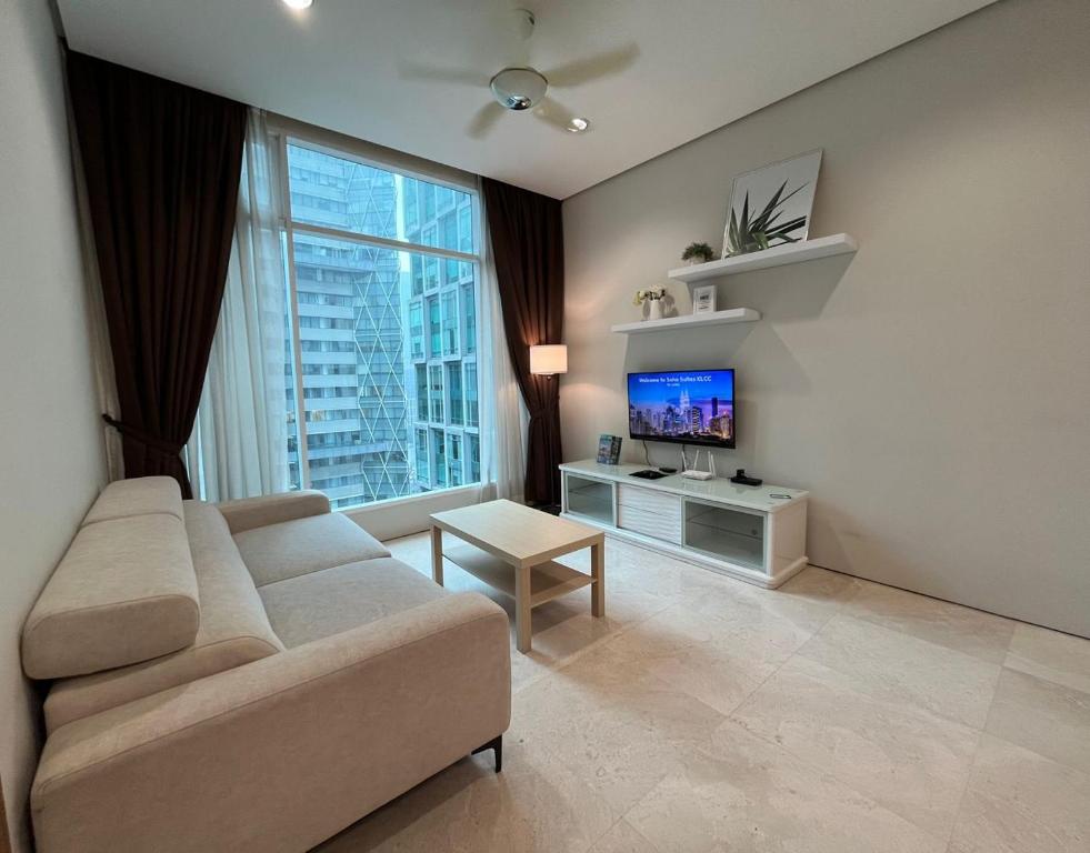 Soho Suites KLCC في كوالالمبور: غرفة معيشة مع أريكة وتلفزيون بشاشة مسطحة