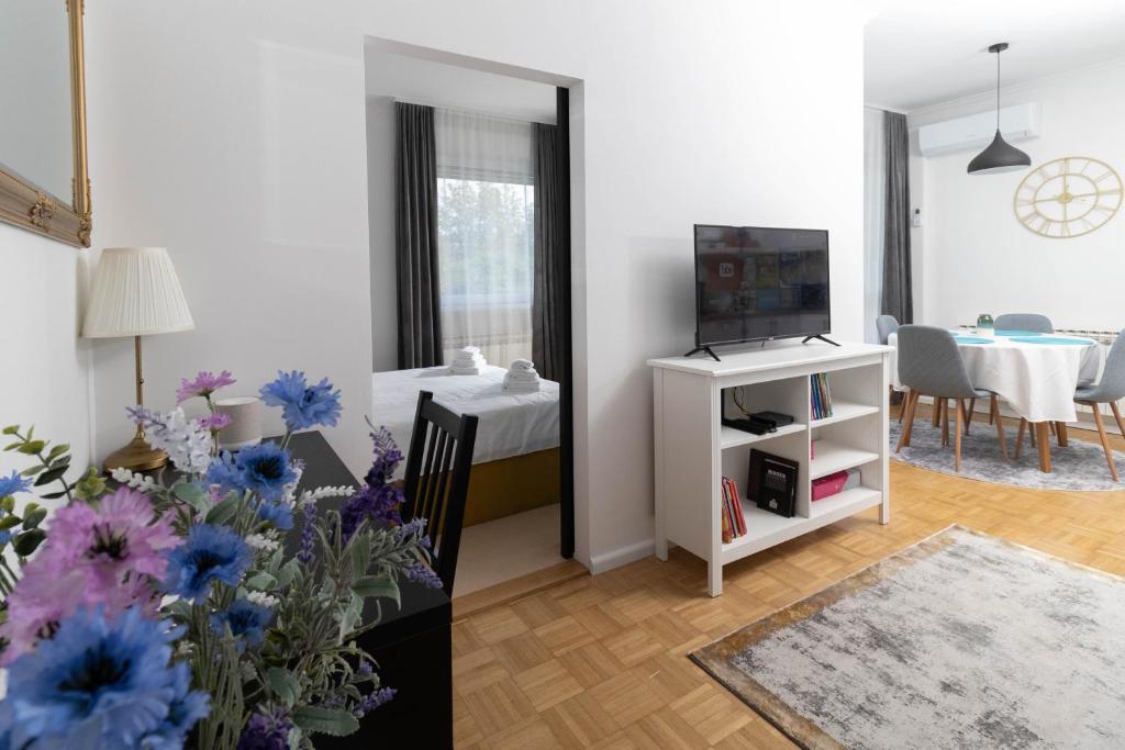 a living room with a tv and a table with flowers at Apartman Čuić in Vinkovci