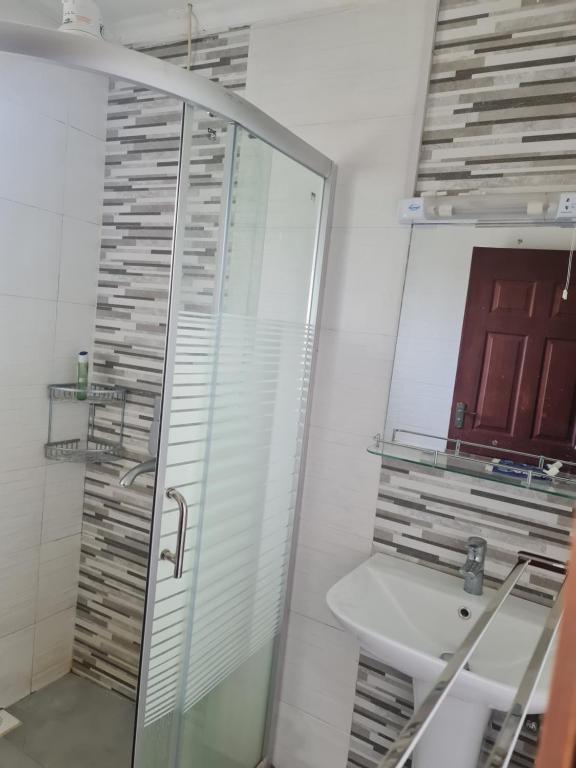 a bathroom with a shower and a sink and a mirror at Stay with Eve in Kitale