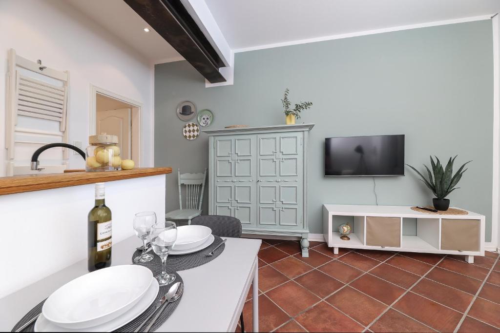 uma sala de estar com uma mesa com copos de vinho e uma televisão em Apartment FERIA 1 em Opatija