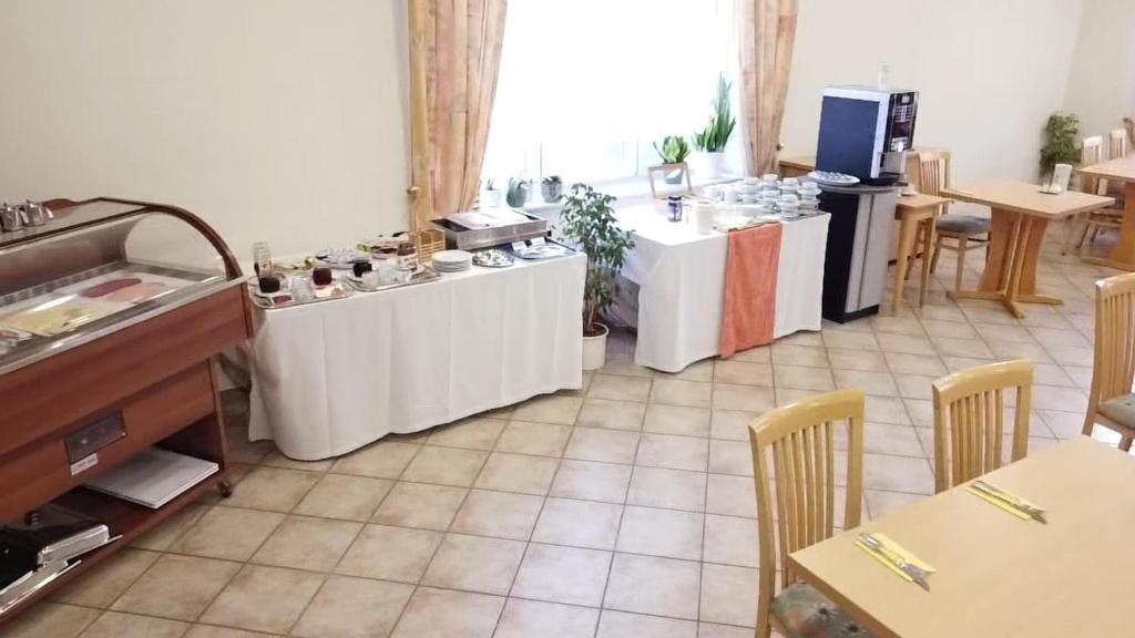 a kitchen with white tables and chairs in a room at Hotel Sorella in Ittlingen