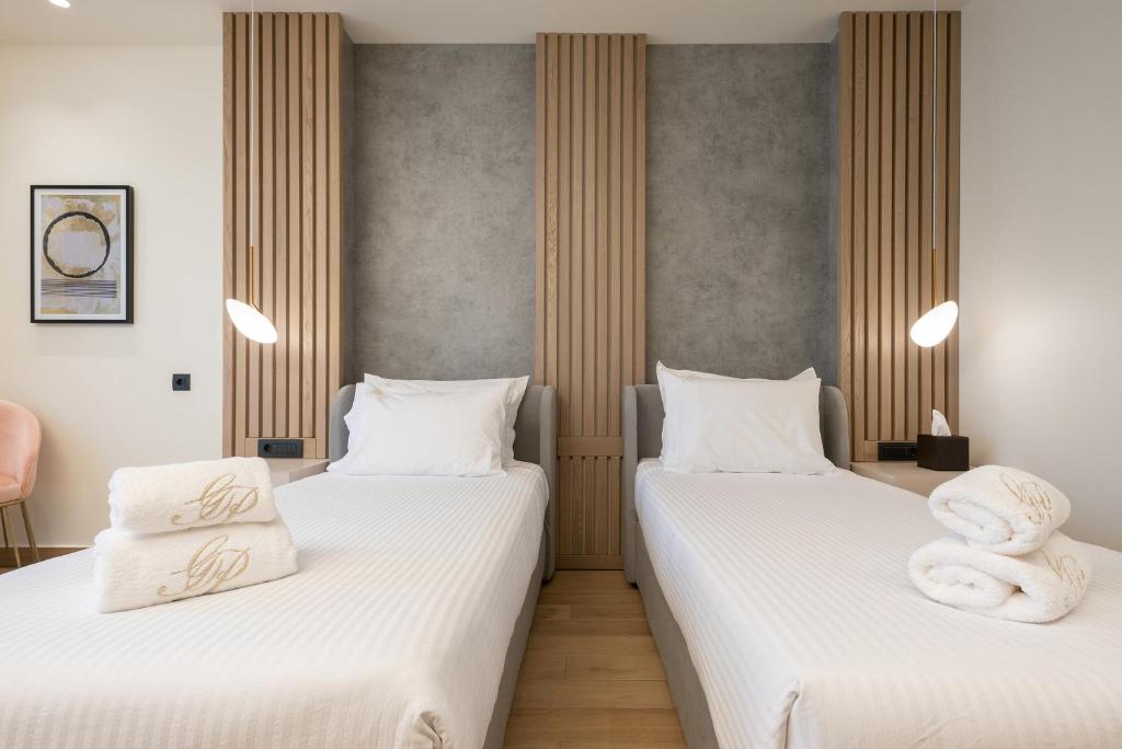 two beds in a room with white sheets and towels at GRAND PATELLI in Myrina