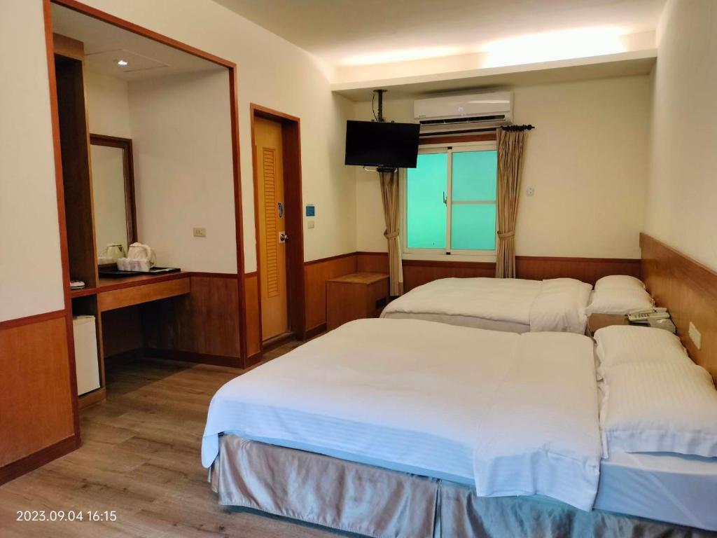 a hotel room with two beds and a television at Rainbow Resort Hotel in Wenquan