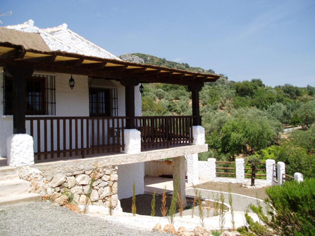 a house with a porch and a bench in front at Villa La Margarita Rocabella in El Chorro