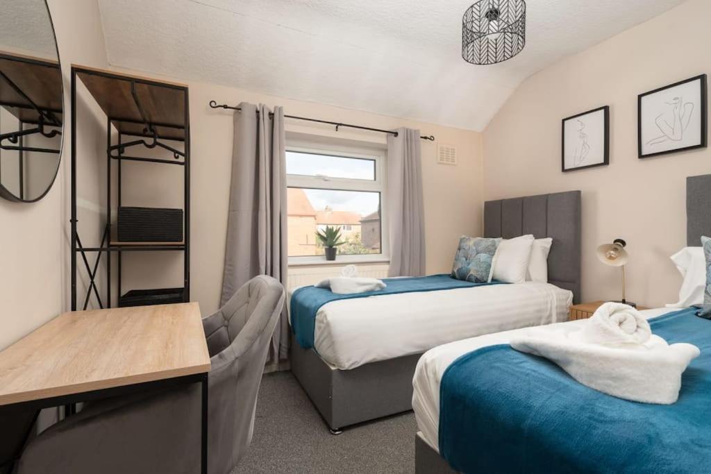 een slaapkamer met 2 bedden, een bureau en een raam bij Alexandra - WiFi Parking Garden in Walton le Dale