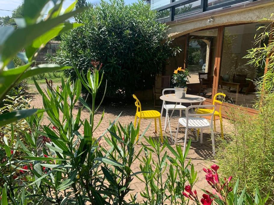 une terrasse avec des chaises jaunes, une table et des chaises dans l'établissement Le gîte des Tourterelles, à Belleville-sur-Saône