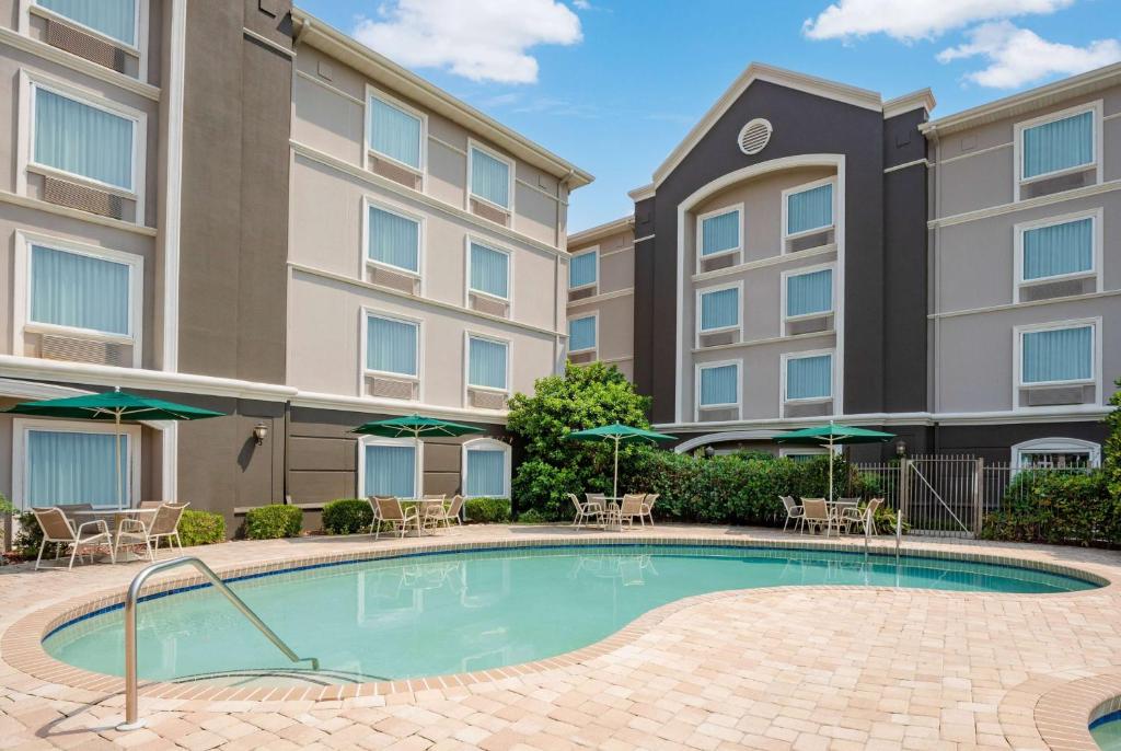 a swimming pool in front of a building with chairs and umbrellas at La Quinta by Wyndham Myrtle Beach Broadway Area in Myrtle Beach
