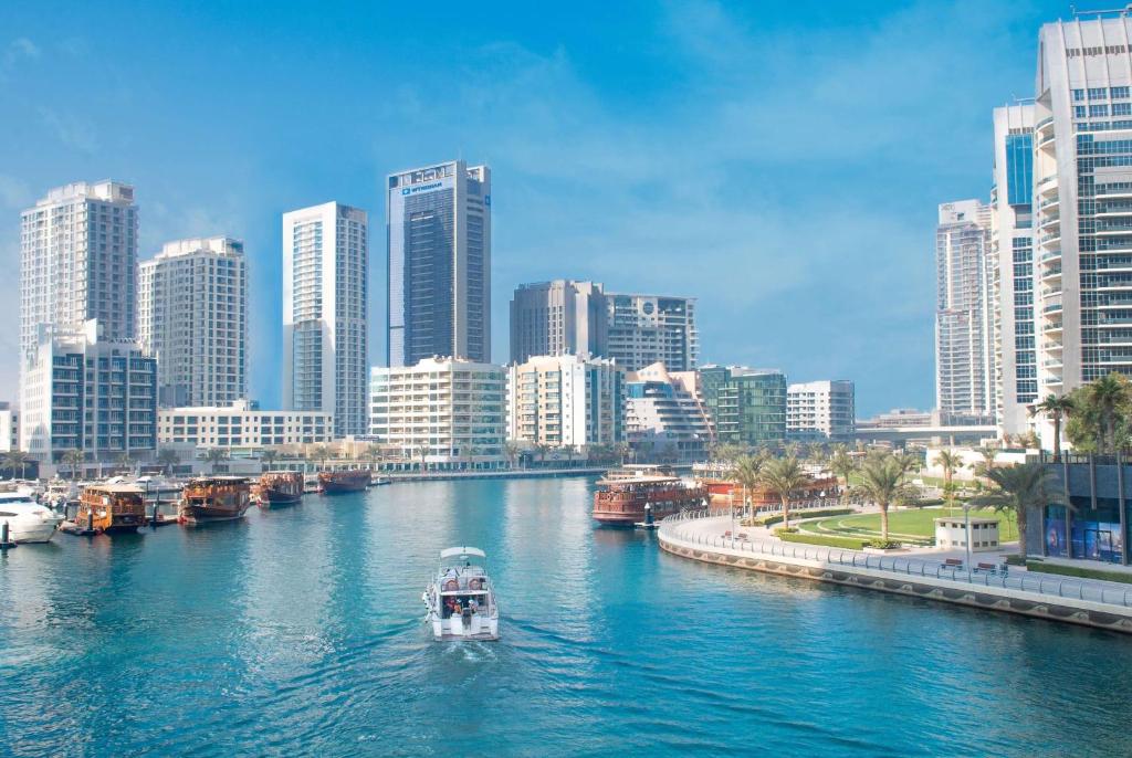 łódź w rzece w mieście z wysokimi budynkami w obiekcie Wyndham Dubai Marina w Dubaju