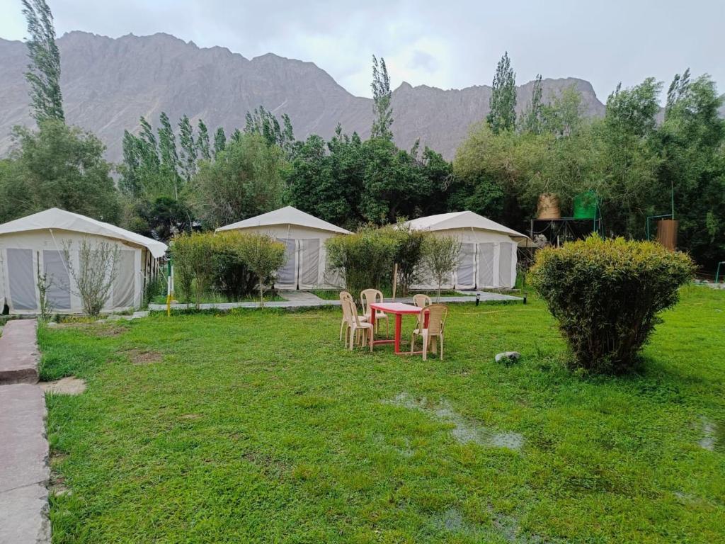 een tuin met een tafel, stoelen en tenten bij The Mountain Camp - Nubra in Hundar