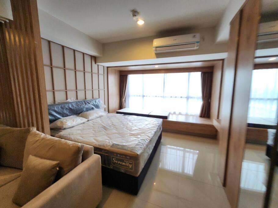 een slaapkamer met een bed, een bank en een raam bij Irvine Suites Lantai 26-I2618 in Cikarang