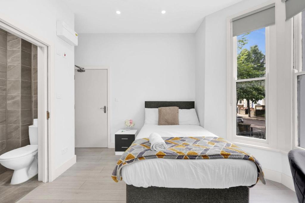 ein weißes Schlafzimmer mit einem Bett und einem Badezimmer in der Unterkunft Luxury Hackney Suites in London