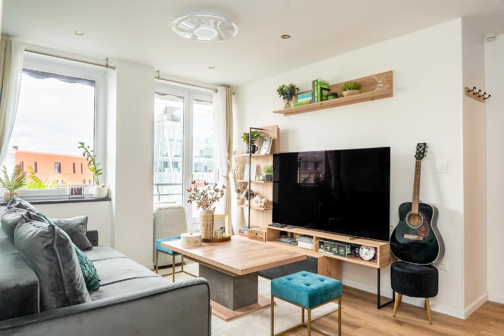 - un salon avec un canapé, une télévision et une guitare dans l'établissement Captivating air-conditioned apartment by Paris, au Kremlin-Bicêtre
