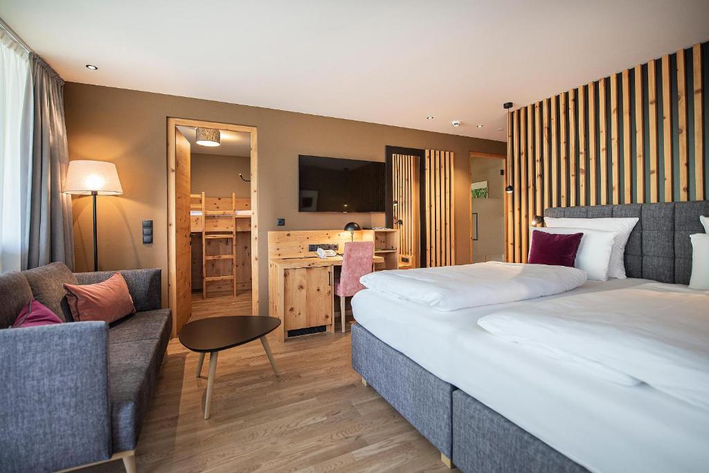 um quarto de hotel com uma cama grande e um sofá em Vitalpina Hotel Waldhof em Rablà