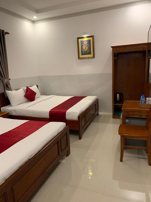 ein Hotelzimmer mit 2 Betten und einem Tisch in der Unterkunft Khách Sạn Chiêu Chương in Ấp Bình Hưng