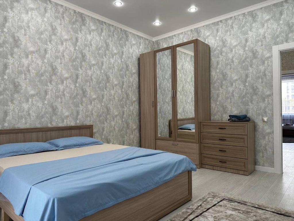 - une chambre avec un lit et un grand miroir dans l'établissement Expo Avenue, à Taldykolʼ