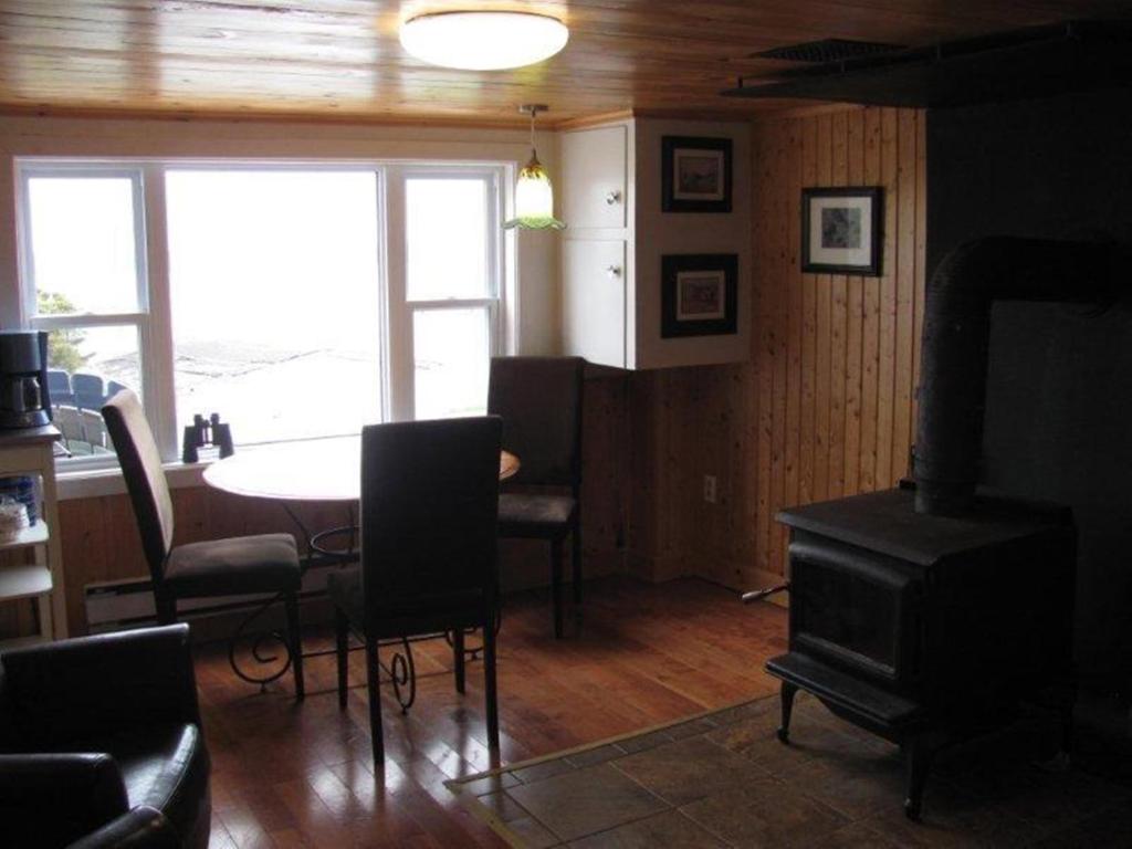 sala de estar con mesa y comedor con fogones en Wolf Cove Retreat House, en Amherst Cove