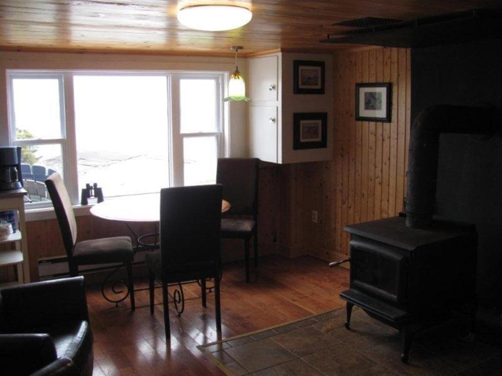 a living room with a table and a dining room with a stove at Wolf Cove Retreat House in Amherst Cove