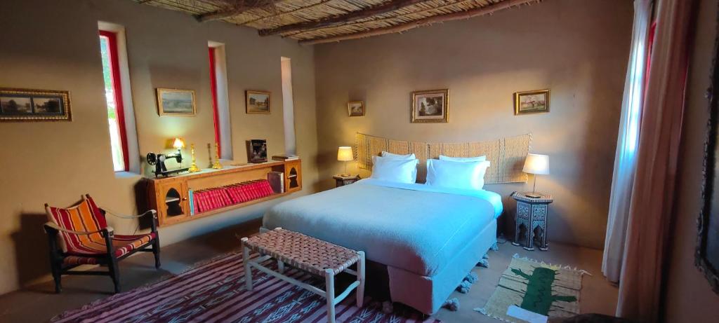 - une chambre avec un lit blanc et une chaise dans l'établissement Dar Tawarta Guest House Dakhla, à Dakhla