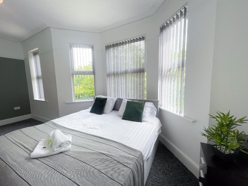 a bedroom with a bed with white sheets and windows at Rock Lane House by Serviced Living Liverpool in Rock Ferry