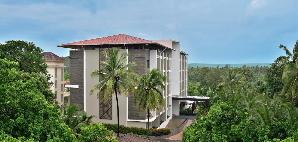 een gebouw met palmbomen ervoor bij Citadines Arpora Nagoa Goa in Arpora