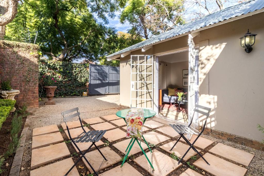 un patio con tavolo e sedie di fronte a una casa di Jeppe house cottage a Pretoria