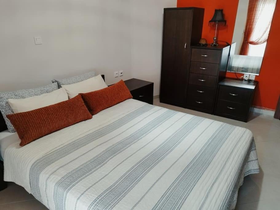 コザニにあるEvaggelia's Apartments 5 Οικογενειακό Διαμέρισμαのベッドルーム1室(オレンジ色の壁のベッド1台、ドレッサー付)