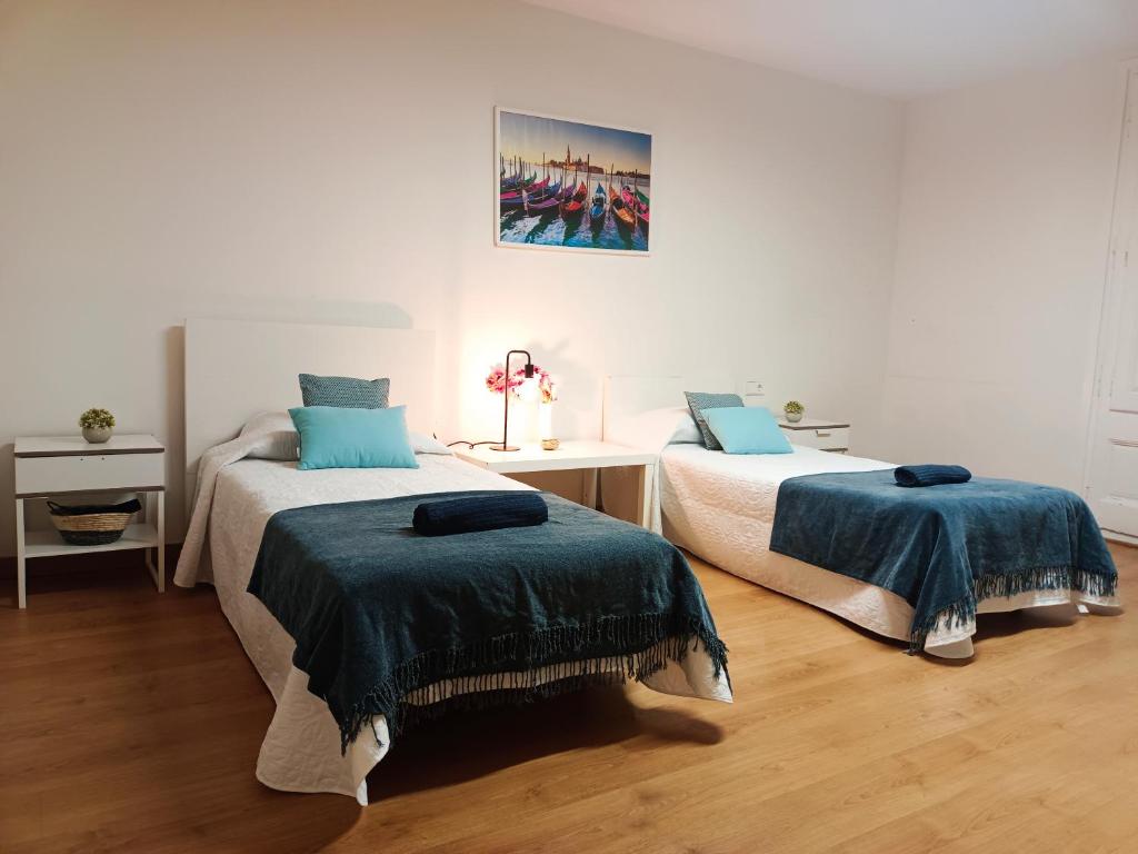a bedroom with two beds with blue comforters at By Cathedral Rooms in Barcelona