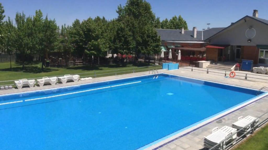 a large blue swimming pool with chairs and a house at Hotel Lasa Sport in Valladolid