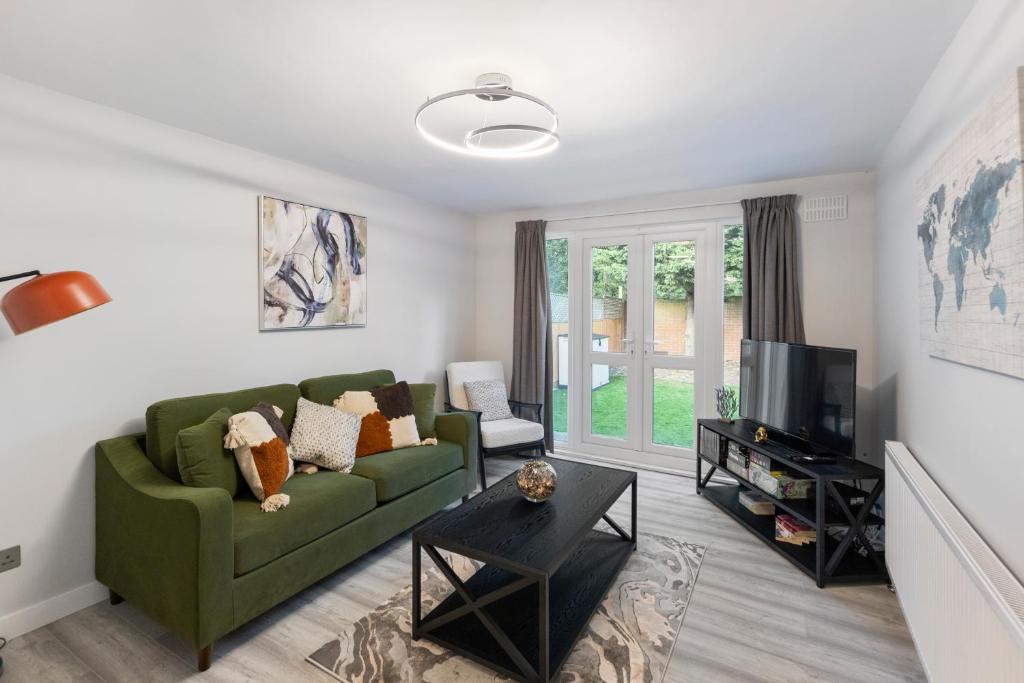 a living room with a green couch and a tv at Stunning 2 Bedroom House with Garden BBQ - Hampstead Heath Park in London
