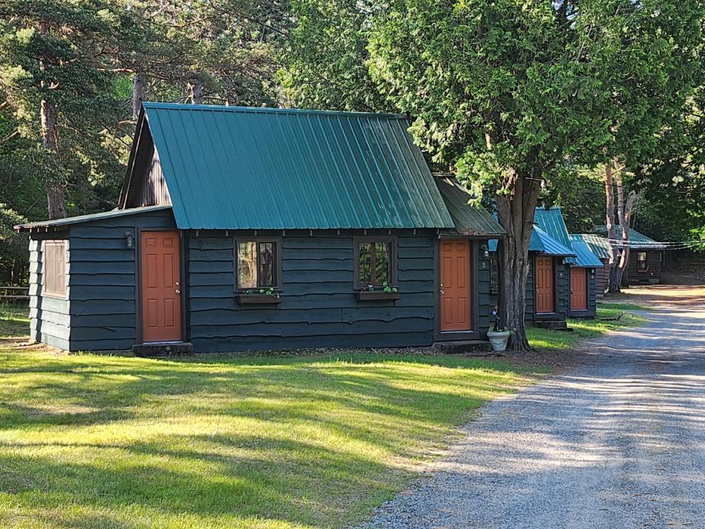 a black cabin with red doors and a green roof at Moreno's Cottages in Saranac Lake