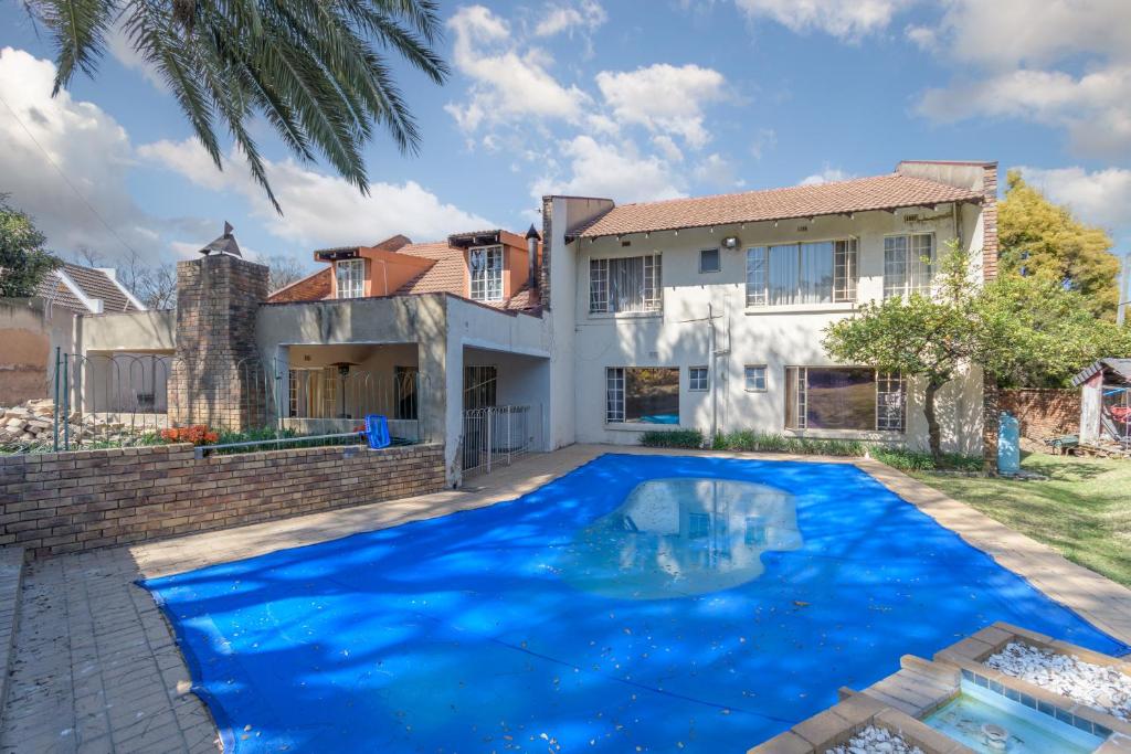 a large blue swimming pool in front of a house at Royal Olympia Lodges & Safaris RSA in Sandton