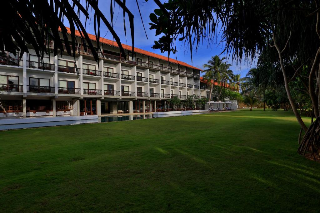 a large building with a green lawn in front of it at Temple Tree Resort & Spa in Bentota